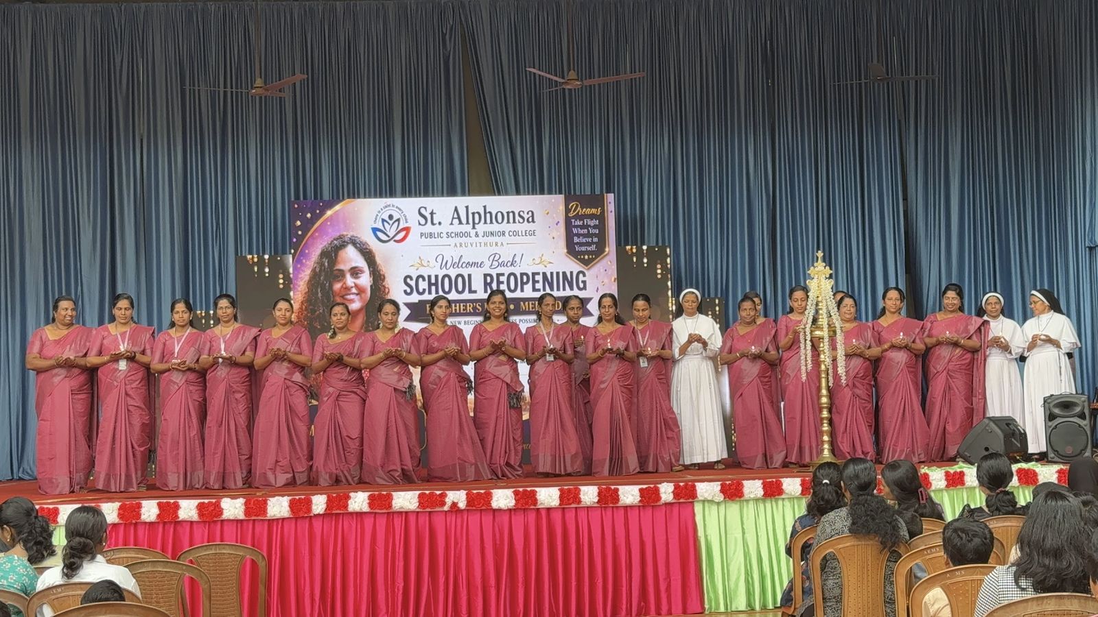 Teachers holding oil lamps on stage during the school reopening ceremony