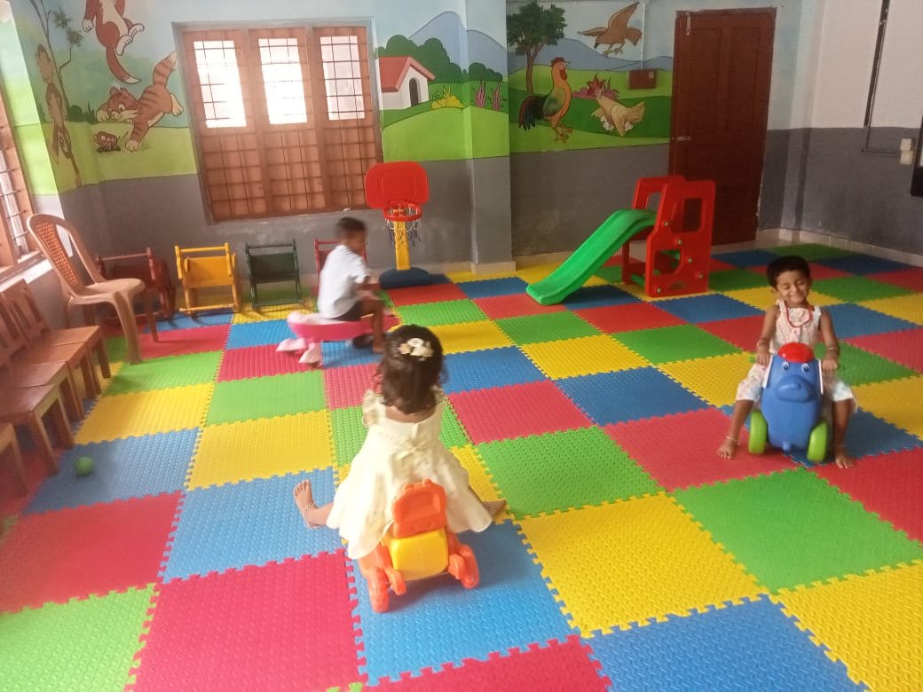 Two small girls on ride-on toys in the pre-primary play room