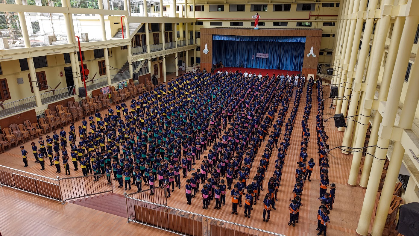 Wide view from an upper balcony of the entire school gathered for morning assembly