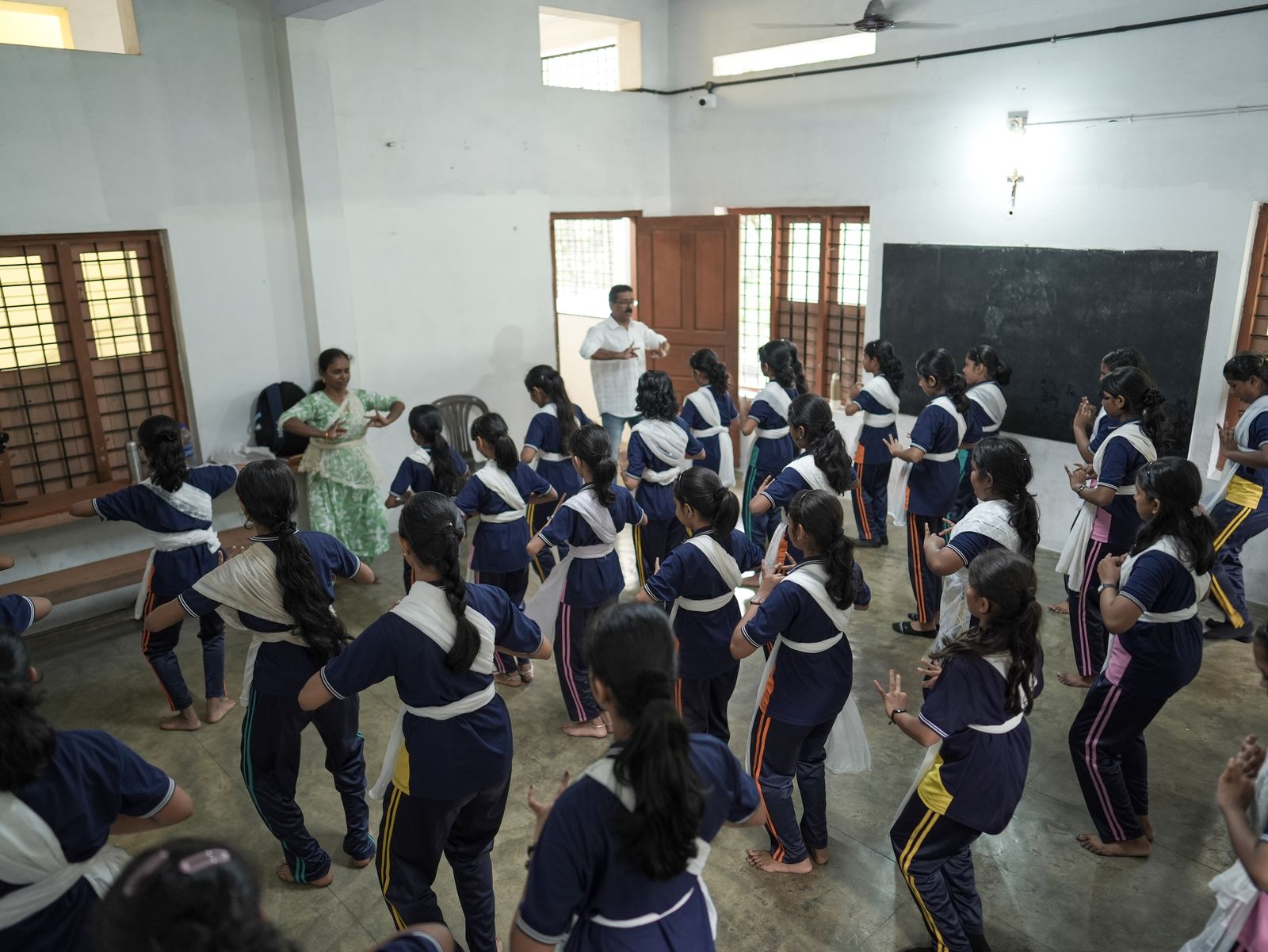 Students practicing classical Indian dance steps under the guidance of two instructors