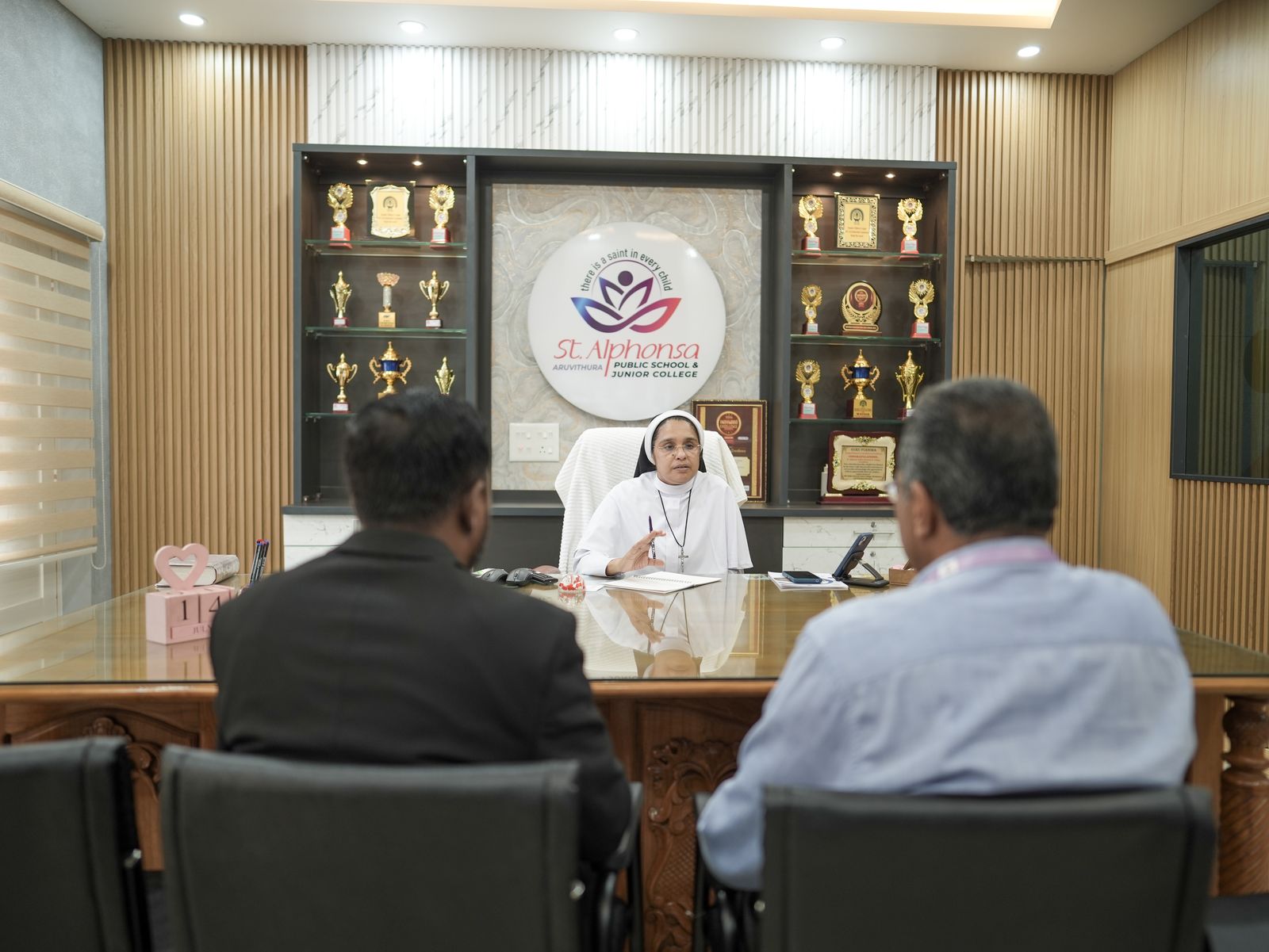 Principal Sister Sindhu George seated at her desk during a meeting with visitors