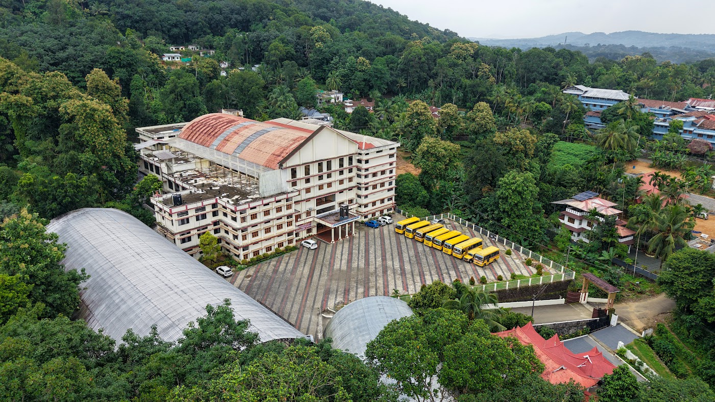 Overhead drone photo of the main school building with yellow buses parked in courtyard