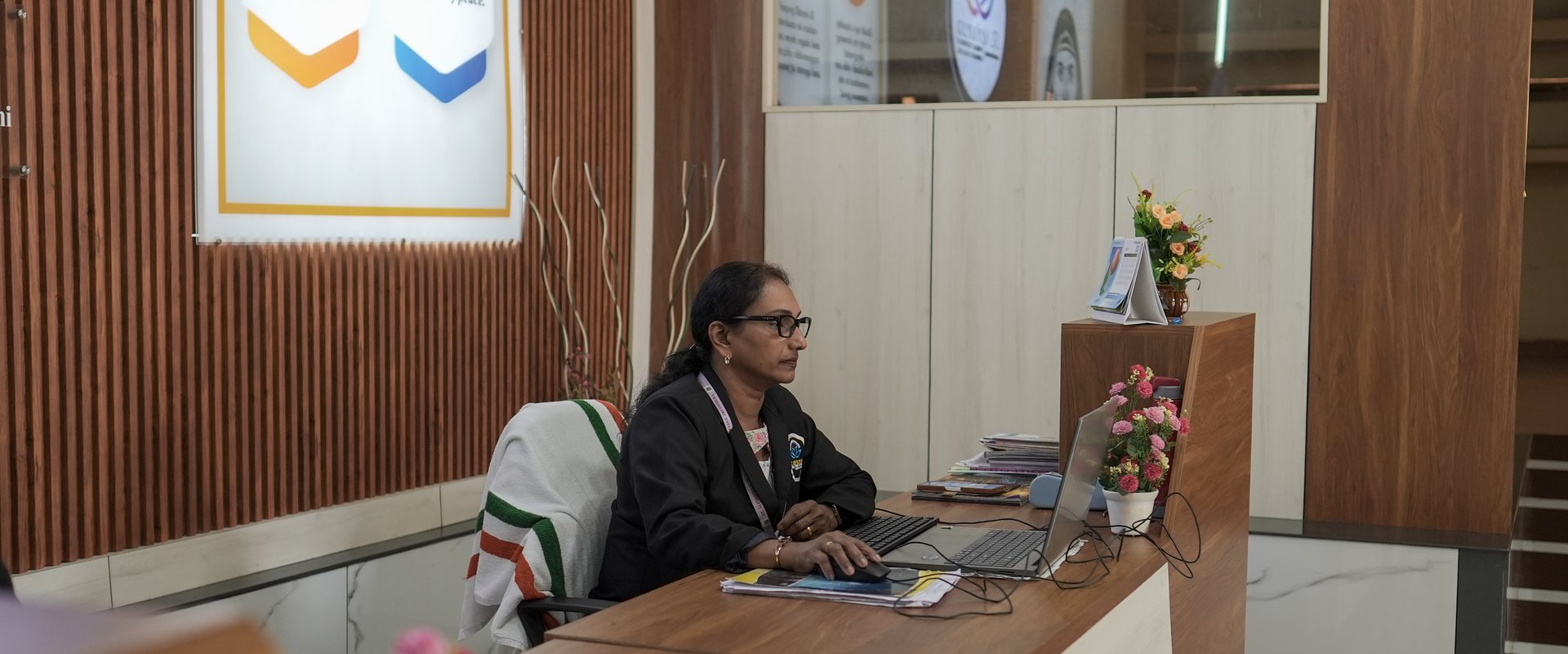 A staff member working at a computer behind the front reception desk of the school